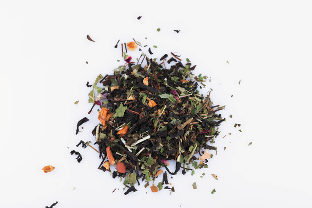 горсть сухого чая из листьев, фруктов и цветов на белом фоне крупным планом - Фото, изображение