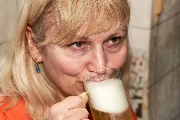 Signera with white hair drinks beer from a transparent mug - Fotografie, Obrázek