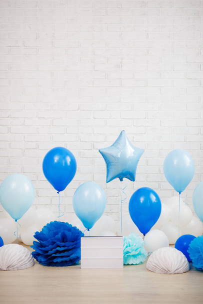 birthday celebration concept - blue air balloons, paper balls and blank lightbox with copy space over white brick wall background - 写真・画像