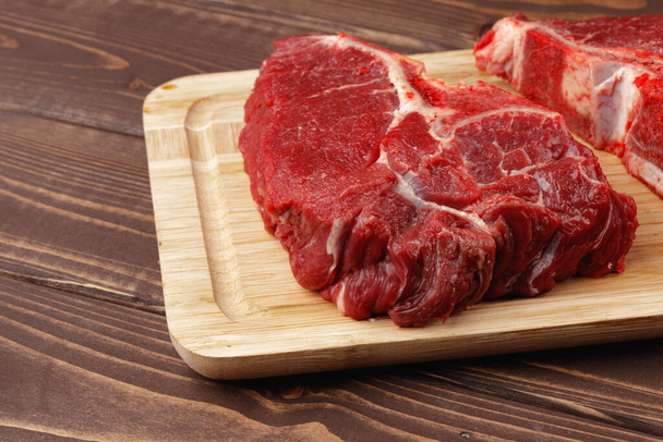 Beef tenderloin on wooden board on wooden table - Zdjęcie, obraz