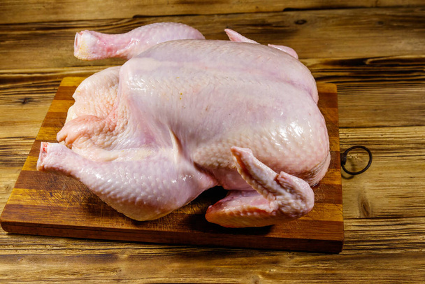 Rauwe hele kip op een houten tafel - Foto, afbeelding
