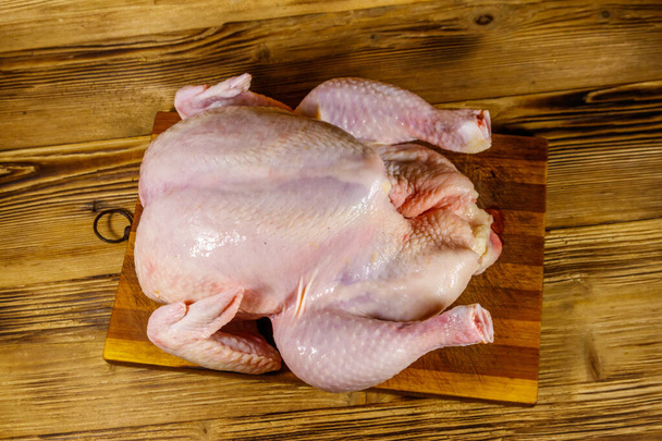 Pollo entero crudo en una mesa de madera. Vista superior - Foto, Imagen