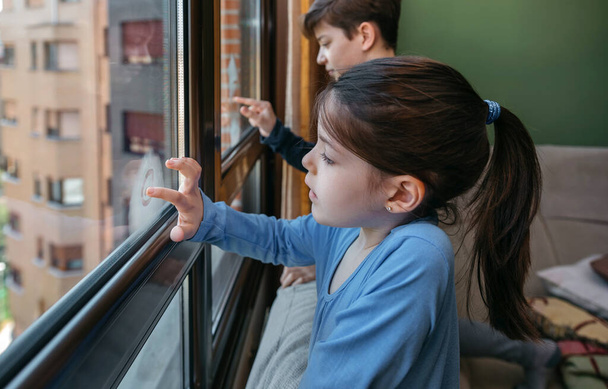 Two children in coronavirus lockdown drawing on the window - Foto, imagen