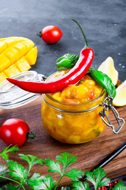  Spicy mexican salsa sauce with mango, chili, tomatoes and basil in a jar close up vertical photo - Valokuva, kuva