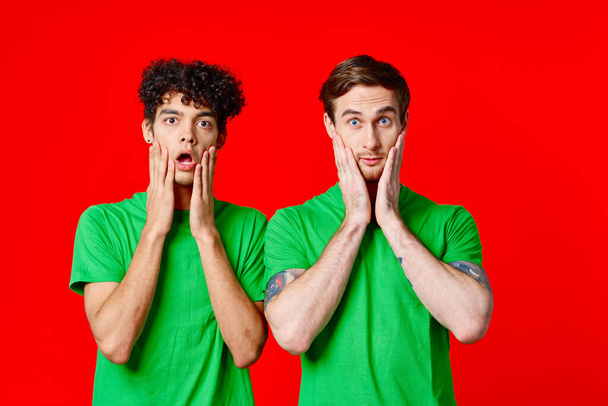 Des amis joyeux en t-shirts verts s'accrochent au visage de l'émotion - Photo, image