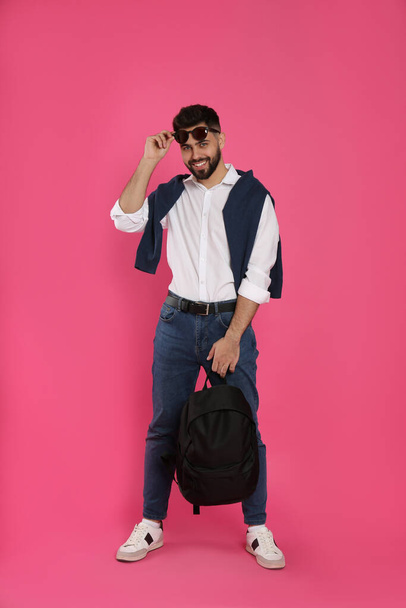 Молодой человек со стильным рюкзаком на розовом фоне - Фото, изображение