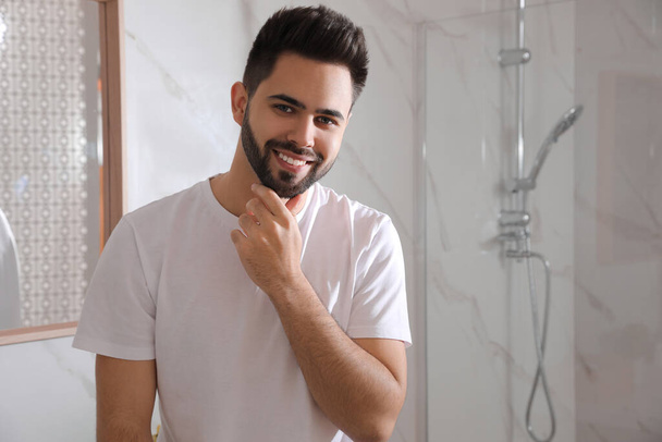 Handsome young man after shaving in bathroom, space for text - Φωτογραφία, εικόνα