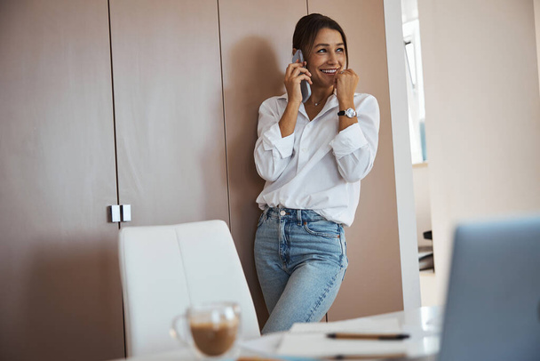 Όμορφη χαρούμενη γυναίκα που έχει τηλεφωνική συνομιλία στη δουλειά - Φωτογραφία, εικόνα