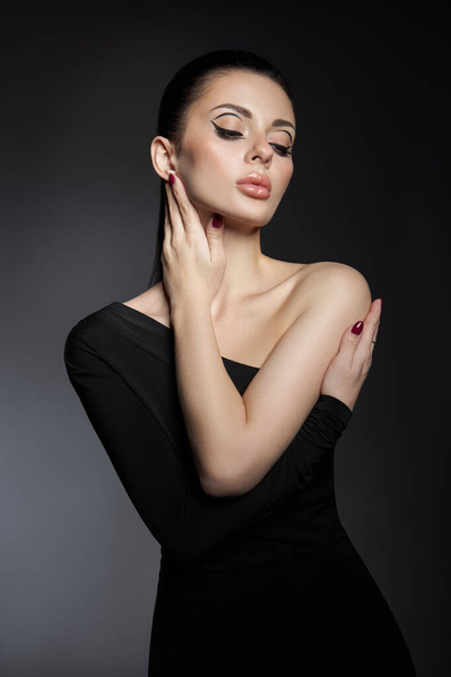 Classic makeup on woman face, beautiful big eyes. Fashion Perfect makeup, expressive eyes on girl face, smooth black eyebrows, licked brunette hair. Portrait woman on dark background - Fotoğraf, Görsel