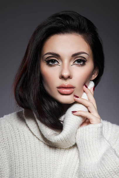 Beauty portrait of woman in white sweater, perfect evening makeup on dark background. Perfect skin without wrinkles, professional beauty makeup, long black hair - Fotografie, Obrázek