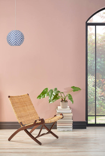 Sala da parete rosa con sedia di vimini e pianta, stile decorazione della lampada. - Foto, immagini