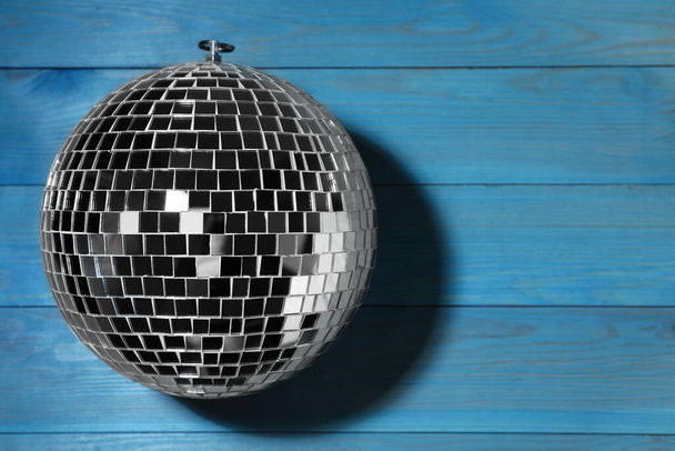 Shiny disco ball on blue wooden background, top view. Space for text - Zdjęcie, obraz