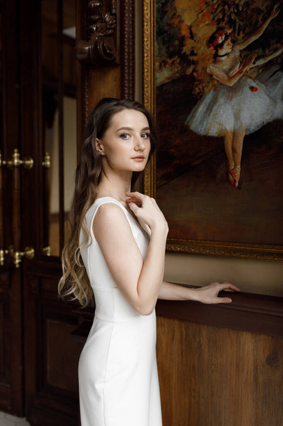 A trendy image of the bride in a dark interior, laconic European style. A stylish modern bride in a white dress with a cutout, a conceptual image. - Foto, imagen