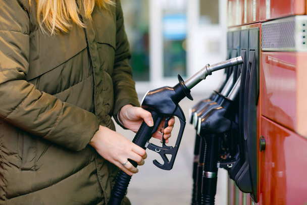 Close-up of hands of woman at self-service gas station, hold fuel nozzle and refuel the car with petrol, diesel, gas. Close up of filling auto with gasoline or benzine. Self service gas pump - Photo, Image