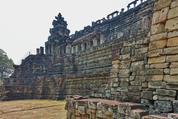アンコールの古代寺院の遺跡。階段が建物の上部につながっています。風化した石に彫刻の跡がある。高い塔、空に対して老朽化したコロネード。カンボジア - 写真・画像