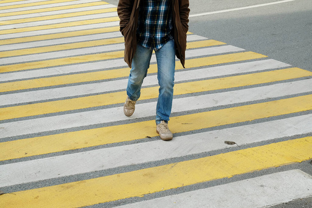 Muž přecházející ulici na bílé a žluté pruhy pěší přechod - Fotografie, Obrázek