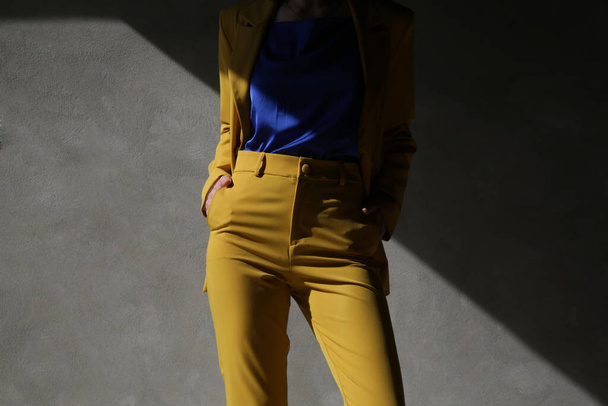 黄色のテーラードスーツのファッショナブルな若い女性. - 写真・画像