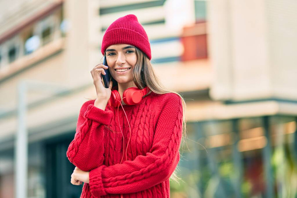 Jeune femme hispanique parlant sur le smartphone en utilisant des écouteurs à la ville. - Photo, image