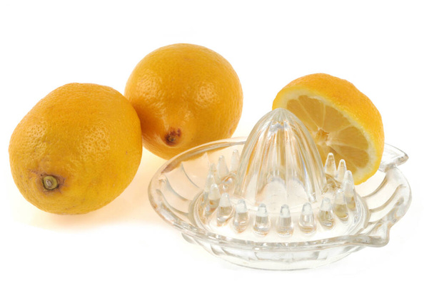 Ολόκληρα λεμόνια και μισό λεμόνι με έναν αποχυμωτή κοντά σε λευκό φόντο - Φωτογραφία, εικόνα