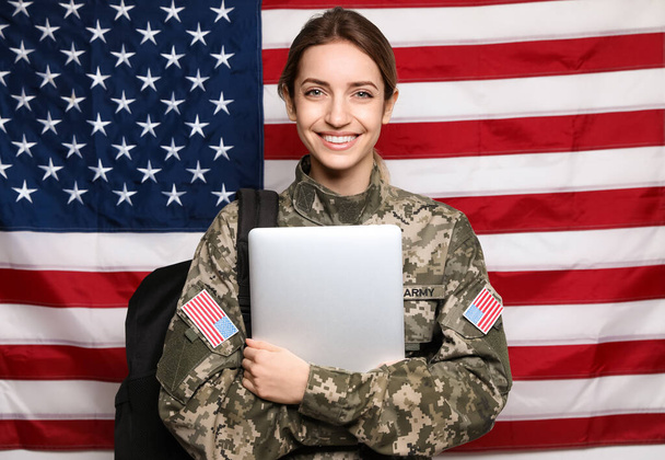 アメリカ国旗に対するバックパックとラップトップを持つ女性士官候補生。軍事教育 - 写真・画像