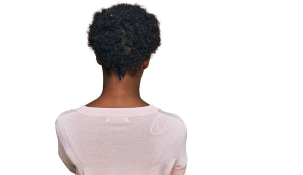 Молода афроамериканська дівчина в повсякденному одязі стоїть спиною і дивиться на неї зі схрещеними руками.  - Фото, зображення