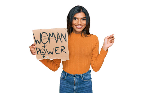 Jovem transexual latina transexual mulher segurando mulher poder banner sorrindo feliz apontando com a mão e o dedo para o lado  - Foto, Imagem