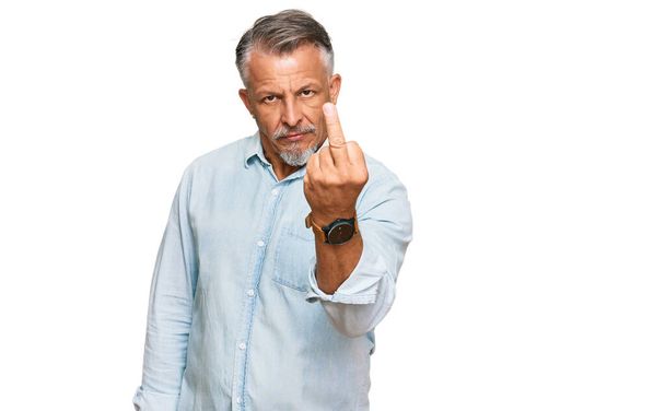 Чоловік середнього віку у сірому одязі, що показує середній палець, неввічливий і грубий хуй вираз
  - Фото, зображення