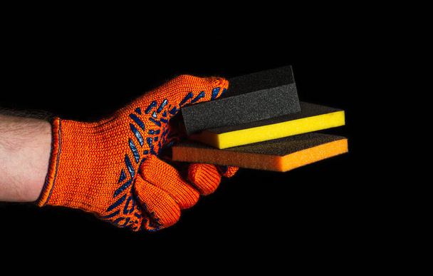 Рука будівельника в рукавичці тримає або дає абразивні інструменти крупним планом на ізольованому чорному тлі. Ідея створення успішної роботи. Вільний рекламний простір
. - Фото, зображення