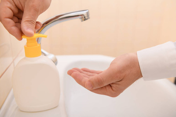 kézmosás szappannal vagy géllel folyó víz alatt a mosdókagylóban, tisztaság és higiénia, férfi kéz fehér ingben - Fotó, kép
