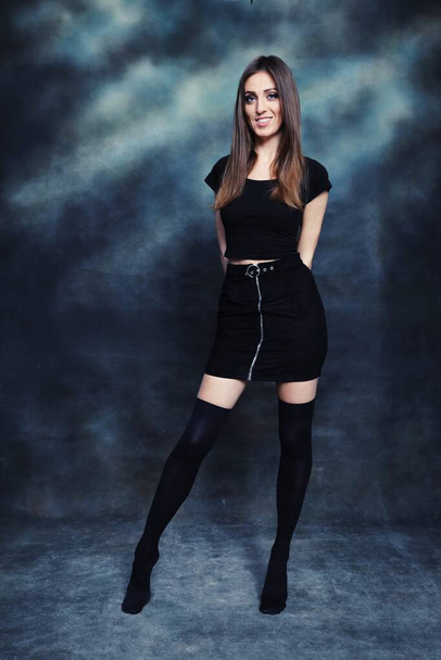 Beautiful, positive brunette girl posing in studio on canvas background. Relaxation, elegance, fashion concept. - Fotó, kép