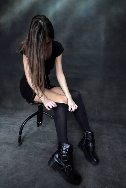 Krásná, pozitivní brunetka dívka pózující ve studiu na plátně pozadí. Relaxace, elegance, módní koncept. - Fotografie, Obrázek