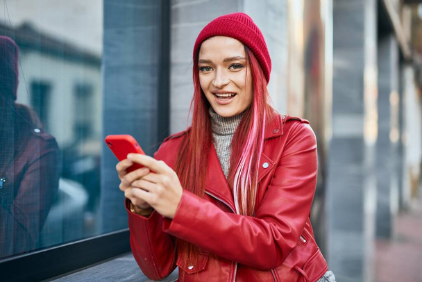 Giovane ragazza caucasica sorridente felice utilizzando smartphone in città. - Foto, immagini