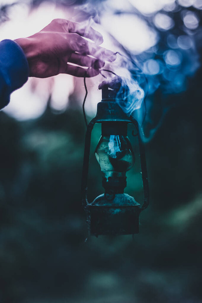 Un coup vertical de la main d'un homme tenant une vieille lampe avec la fumée qui en sort - Photo, image