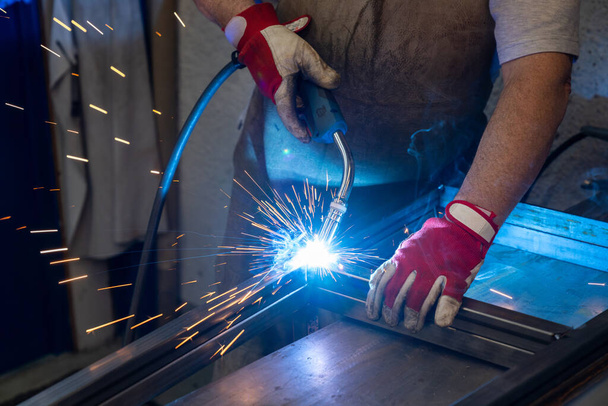 A metal worker welding and fabricating a metal frame for a garden patio - Photo, Image