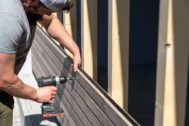 Kova rakennusalan työntekijä soveltaa puinen sivuraide autotallin ja porat ruuvit - Valokuva, kuva