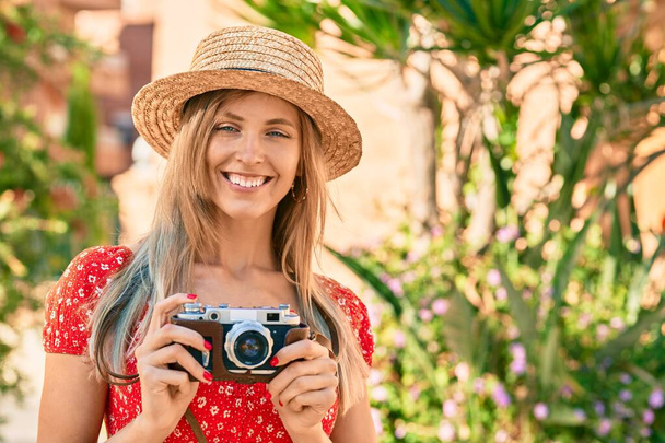 Joven mujer turista rubia con estilo de verano utilizando la cámara vintage en el parque - Foto, imagen