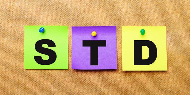 On a beige background, multi-colored stickers for notes with the word STD - Fotó, kép