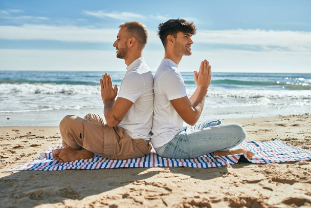 Jeune couple gay faire du yoga assis à la plage. - Photo, image