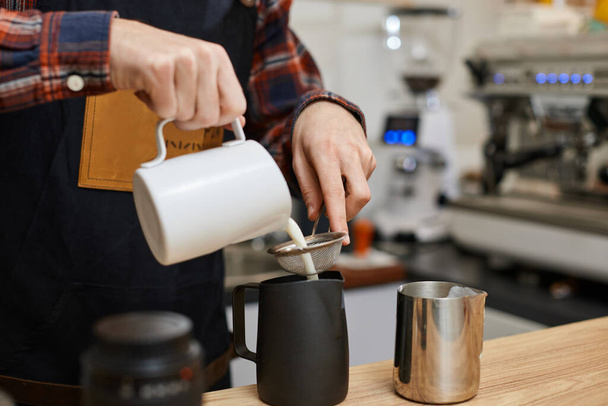 Caucasian man pouring hot milk in coffee. - 写真・画像