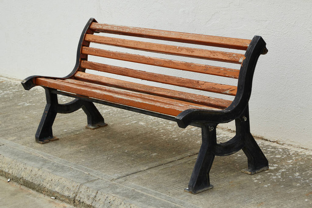 a brown street bench against a white wall. - Photo, Image