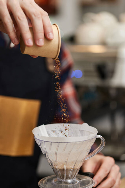 male hands pouring grounded coffee in filter. - Photo, image