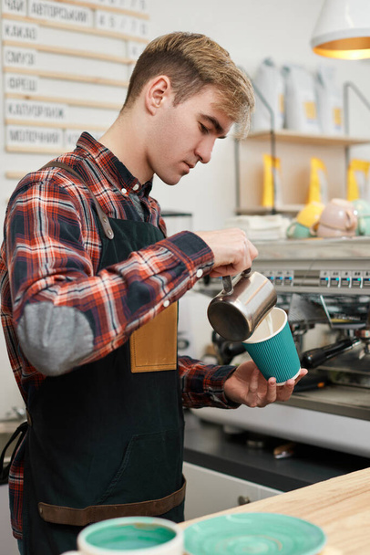 barista in apron pours fresh coffee into a cup - Foto, Bild