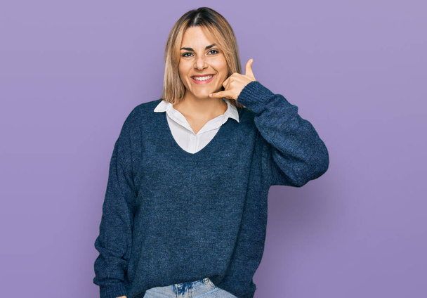 Jeune femme caucasienne portant des vêtements décontractés souriant faire geste de téléphone avec la main et les doigts comme parler au téléphone. communiquer les concepts.  - Photo, image