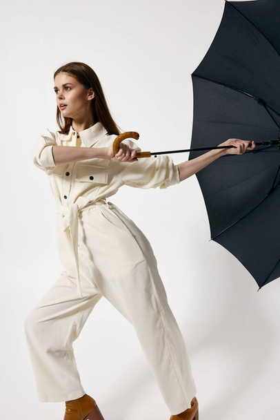 Женщина в белом комбинезоне держит зонтик от ветра на изолированном фоне - Фото, изображение