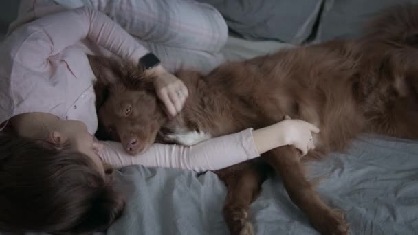 Ragazza con il suo cane coccole sul letto - Filmati, video