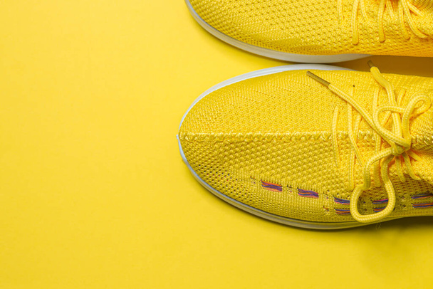 Baskets jaunes sur fond jaune. Chaussures de sport. Concept de mode de vie sain - Photo, image