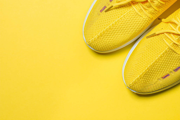 Желтые кроссовки на желтом фоне. Спортивная обувь. Понятие здорового образа жизни - Фото, изображение
