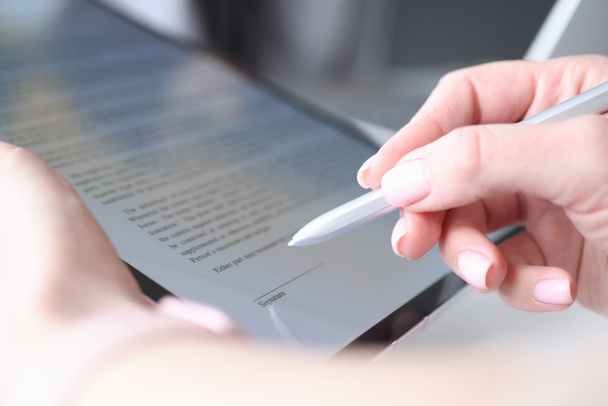 Mujer mano sostiene lápiz óptico y pone una firma electrónica en contrato en la tableta - Foto, imagen