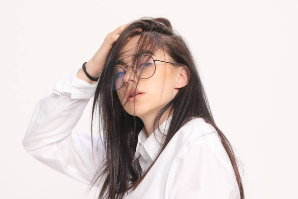 Beautiful caucasian hipster girl with black hair and glasses is posing in studio on isolated background. Style, trends, fashion concept. - Foto, Imagem