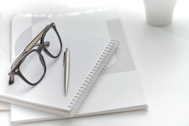 Nahaufnahme einer schwarzen Brille auf einem Ordner mit Dokumenten auf dem Schreibtisch. Nahaufnahme - Foto, Bild
